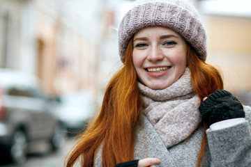 Closeup portrait of happy red haired girl with natural makeup walking down the street. Empty space