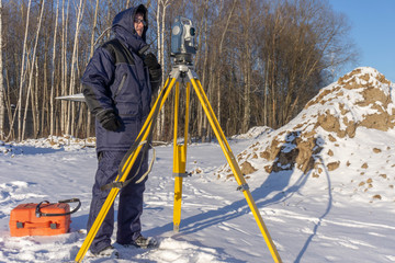 Surveyor conducts surveying in winter at a construction site