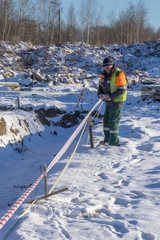 A worker at a construction site shields trenches with a signal tape for cadastral surveying.