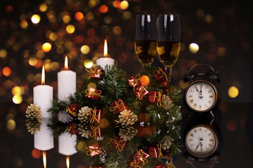 Fototapeta na wymiar Glasses with champagne,candles, clock and Christmas ornaments
