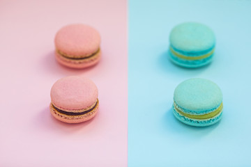 Fototapeta na wymiar Sweet colorful French macaroon biscuits on pink and blue pastel background, top view. Flay lay selection of macarons.