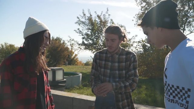 Group of young people standing with skateboards communicates outdoors. Skateboarder people have fun talking in the park.