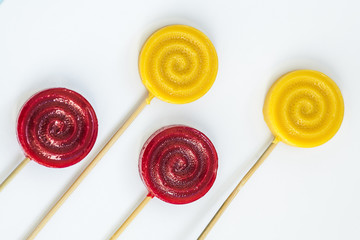Assorted colors yellow and red lollipops isolated on white background, close-up. Top view. Flat lay.