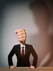 The man in a suit with a head in the form of a fist. Metaphor of an angry boss.