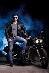 Obraz na płótnie Canvas Cute motorcyclist stands near his motorcycle 
