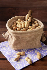 Peanuts in a peel in a bag on a wooden background.