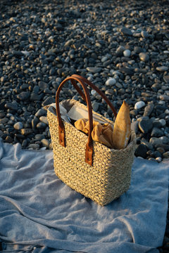 Grocery shopping bag with baget bread, standing on rocky sea shore