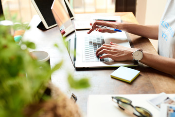 Woman with pen typing on laptop
