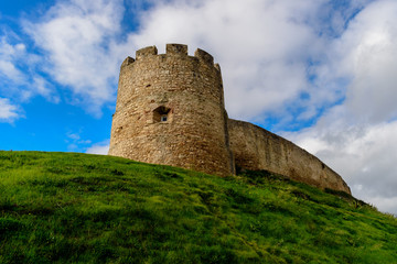 Fototapeta na wymiar Tower and wall of Torres Vedras castle on top of green hill, Portugal