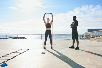 Sportswoman performing exercising with personal trainer.