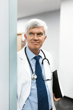 Senior doctor standing on door threshold 