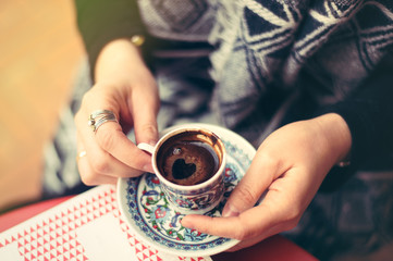 Fototapeta na wymiar Top view to turkish coffee in tradition coffee cup with ornaments in woman's hands