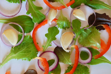 Purple or green basil, Ruccola, purple onion rings, red sweet pepper, garlic, on a white background. Frame from fresh greens. Craft background