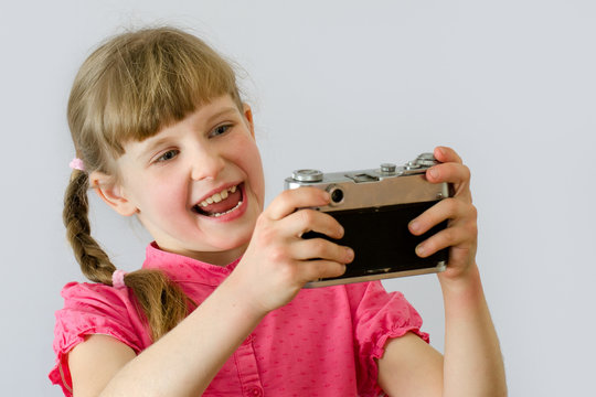 kid, child takes pictures of herself with an old camera