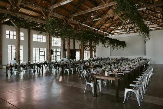 Long harvest tables with simple greenery and copper details in industrial setting for wedding