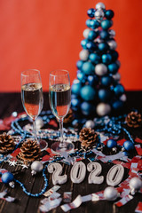 Composition with Christmas and New Year 2020 decorations and two champagne glasses, on bright background