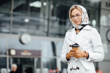 Beautiful woman with coffee cup near office building. 