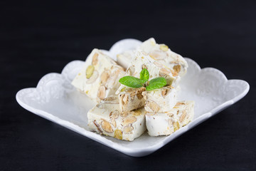 Italian torrone or nougat with almonds and pistachios from Apulia, traditional christmas sweets on black background