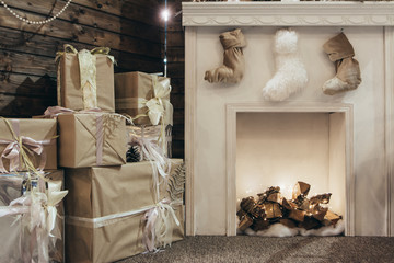 Cozy Christmas decor with photo zone of the fireplace with socks and gifts on a wooden background. Cozy photo of a fireplace and Christmas gifts. Cozy New Year's photo.