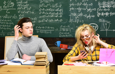 Tutors fill different role than teachers and parents. Old books on a round wooden table. Confident student studying for exam at desk with laptop reading a book.