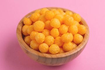 Cheese puff balls in wooden bowl on bright colorful background