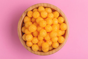 Cheese puff balls in wooden bowl on bright colorful background
