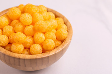 Cheese puff balls in wooden bowl on light background