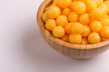 Cheese puff balls in wooden bowl on light background