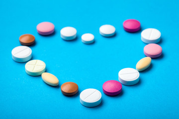 Heart laid out of pills on a blue background, drugs round and oval pills.