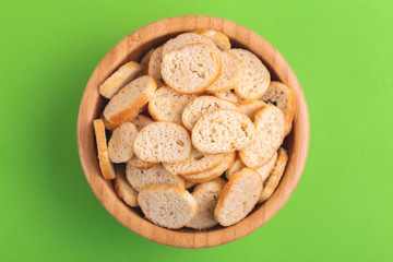 Wheat salted crackers in wooden bowl on bright colored background
