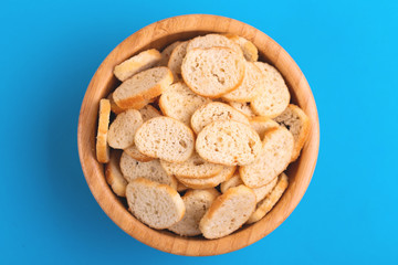 Wheat salted crackers in wooden bowl on bright colored background