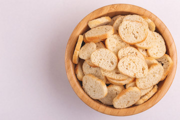 Wheat salted crackers in wooden bowl on light marble background