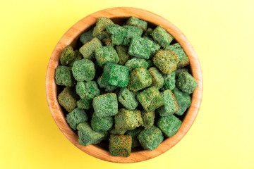 Wasabi flavored crackers in wooden bowl on bright colored background
