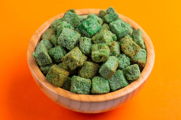 Wasabi flavored crackers in wooden bowl on bright colored background