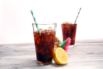 Softdrink with ice cubes, lemon and straw in glass