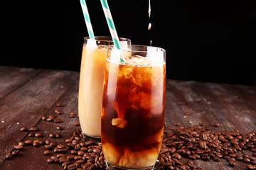 Ice coffee on a rustic table with cream being poured into it showing the texture and refreshing look of the drink