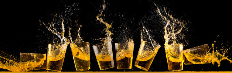 Eight golden tequila shots splashing