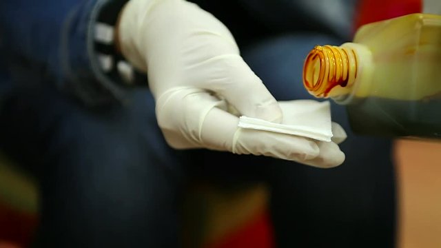 Medical worker puts iodine on gauze close up