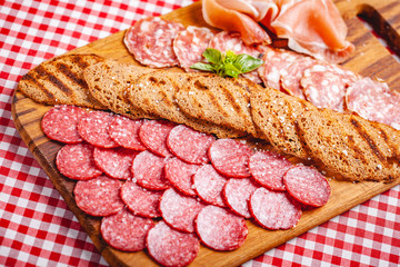 Italian meat and toasted bread on wooden cutting board. Close up
