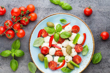 Delicious caprese salad with ripe cherry tomatoes and mini mozzarella cheese balls with fresh basil leaves.