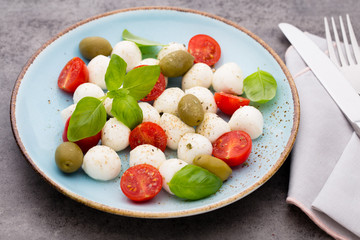 Delicious caprese salad with ripe cherry tomatoes and mini mozzarella cheese balls with fresh basil leaves.