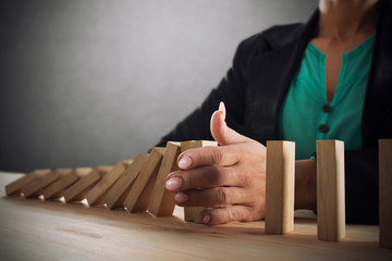 Businesswoman stops a chain fall like domino game. Concept of preventing crisis and failure in...