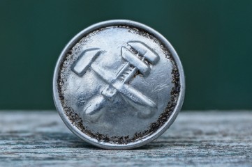 old gray soviet metal button with emblem on table on green background