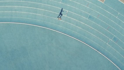 Aerial view of female runner practicing on race track in stadium. Sports woman running on athletics race track. - Powered by Adobe
