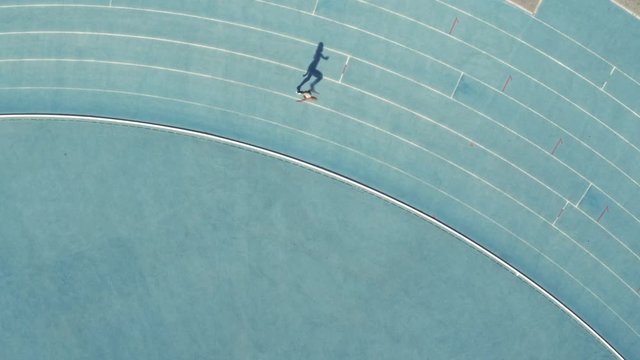 Aerial view of female runner practicing on race track in stadium. Sports woman running on athletics race track.
