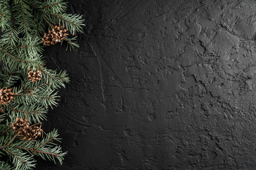 Christmas fir branches and pine cones on dark background with snowflakes. Xmas and New Year theme. Flat lay, top view, space for text