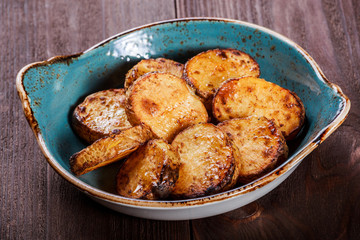 Grilled potatoes in the plate on wooden background. Top view