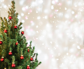 Christmas tree with red Christmas decorations on holiday background with snow, blurred, sparking, glowing. Happy New Year and Xmas theme