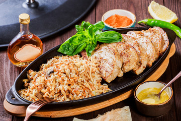 Baked dish of beef, noodles, rice, mushrooms, onions served with butter, spices and cognac in pan on wooden table. Hot Meat Georgian cuisine. Top view