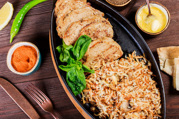 Baked dish of beef, noodles, rice, mushrooms, onions served with butter, spices and cognac in pan on wooden table. Hot Meat Georgian cuisine. Top view